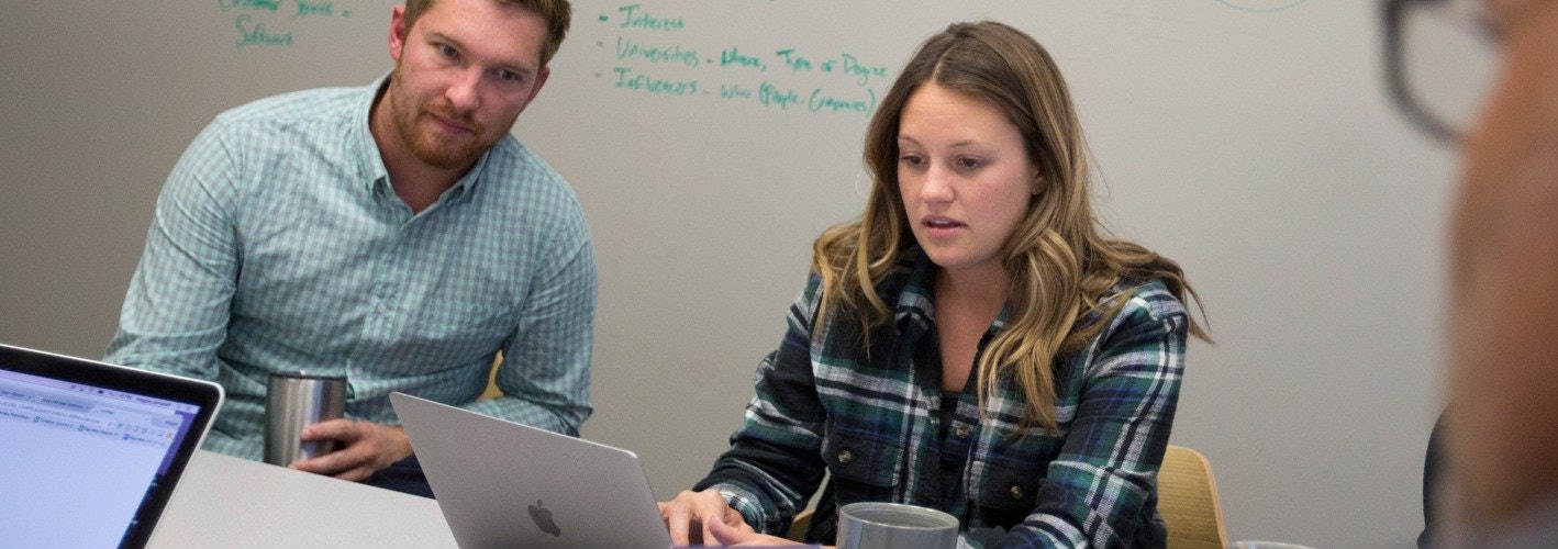 marketers working at a table in front of a whiteboard